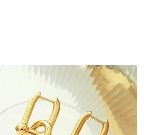 Close-up of gold chain earrings displayed on textured glass with bright metallic finish