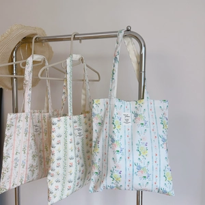 Dettaglio di borse tote in tela a righe con delicate stampe floreali in tre colori
