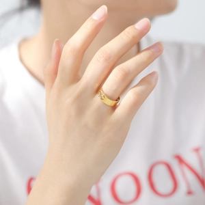 Detail of a hollow spider pattern gold stainless steel ring worn on a finger