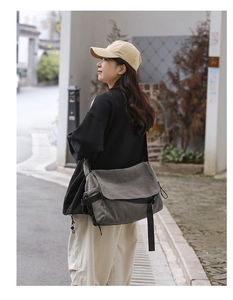 Outdoor shot of a man wearing a large gray canvas messenger bag with adjustable strap