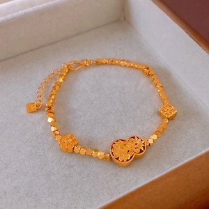 Detail of gold-plated bracelet with flower, gourd and ruyi knot charms on velvet