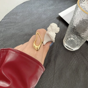 Detailed close-up of golden irregular hollow ring on hand with artistic styling