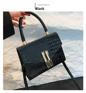 Close-up of black crocodile embossed leather handbag with golden H-shaped hardware