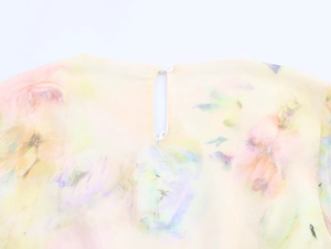 Dettaglio del retro dell'abito in chiffon con chiusura a bottone e stampa floreale acquerello