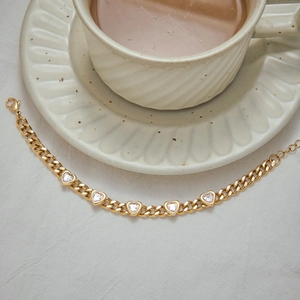 Close-up of golden heart cuban chain bracelet with zircon stones on a tea table