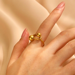 Close-up of a gold minimalist ring featuring a double ball design on champagne silk fabric