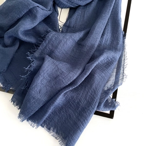Detail of dark blue cotton linen scarf with frayed edges on a clean white background