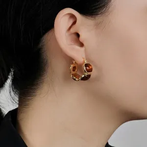 Retro amber resin and 18K gold plated oval hoop earrings on a model’s ear