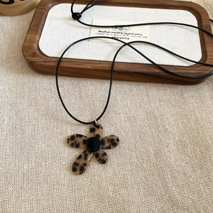 Retro leopard print flower pendant necklace with adjustable black cord on linen base