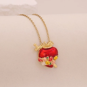 Detailed view of a golden sacred heart necklace with red enamel and floral motifs