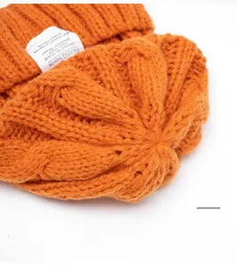 Macro shot of orange knit beanie texture with premium stitching and woven brand tag