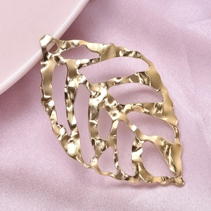 Close-up of golden hollow leaf pendant made of 304 stainless steel with textured detail