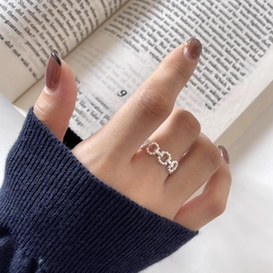 Detail of silver beaded hollow chain ring worn by a model against an aesthetic book backdrop