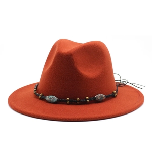 Detail view of rust red fedora hat with ethnic bead decorations and woven black band
