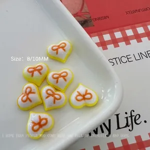 Detailed view of 8mm and 10mm resin heart charms with orange bows for nail art