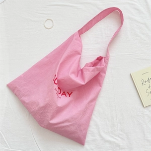 Detail of pink canvas tote bag with red Sunday print on white fabric background