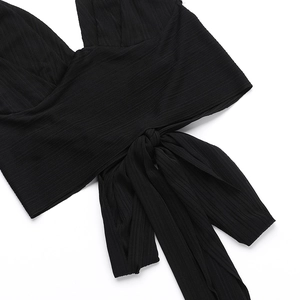 Détail du haut dos nu noir à texture côtelée montrant le nœud et le tissu élastique