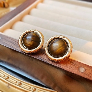 Vintage gold rope frame stud earrings with brown tiger eye stones on wooden jewelry box