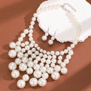 Macro view of multi-layer pearl necklace and matching earrings on stone backdrop