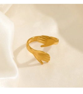 Dettaglio anello abbraccio placcato oro 18K con mani delicate su tessuto di raso