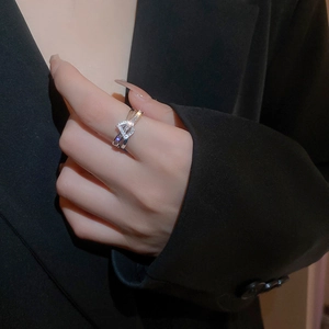 Detail of silver double-layered zircon D ring on model finger against dark suit jacket
