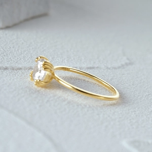 Macro shot of S925 engraved gold ring featuring a six-prong round brilliant gemstone