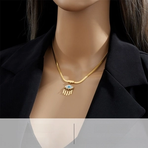 Detail of gold U-shaped snake chain necklace with blue evil eye and Lucky pendant