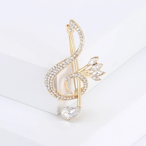 Close-up of golden treble clef brooch with rhinestones on a white geometric block