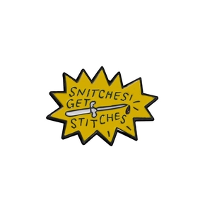 Detailed view of yellow enamel snitches get stitches pin with knife design
