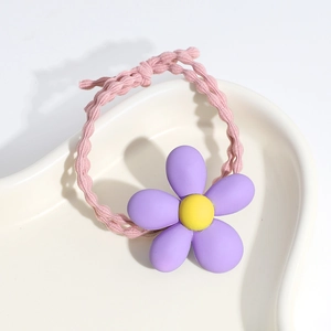 Close-up of pink elastic hair tie with a purple flower on a white ceramic tray