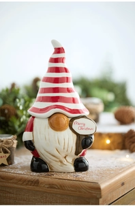 Close-up of ceramic Christmas gnome jar with Merry Christmas sign on wooden surface