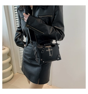 Close-up of black punk crossbody bag with metallic cross details and silver metal studs