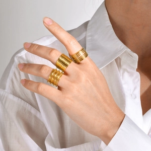 Detail of layered gold stainless steel rings worn on finger, minimalist style
