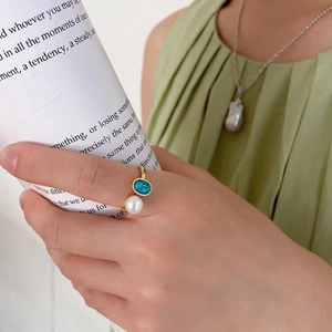 Adjustable gold ring with turquoise and white pearl gemstone on a female model