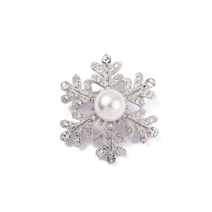 Macro detail of silver snowflake brooch with sparkling rhinestones and center pearl