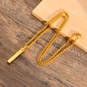 Close-up of golden rectangular tungsten pendant on a woven cord over wood