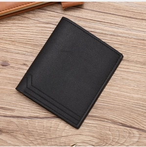 Detail view of black leather wallet with litchi texture on a professional wooden desk