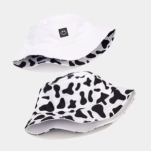 Detail showing cow print and white smiley face pattern on reversible cotton bucket hat