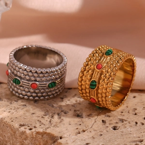 Close-up of gold and silver stainless steel rings with red and green natural stones