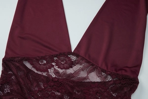 Close-up of burgundy lace patchwork and fine stitching on a deep red halter top