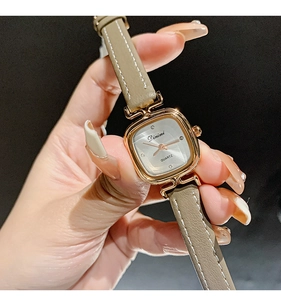 Close-up of elegant square gold watch with beige leather strap and diamond markers