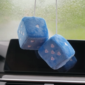 Detail of blue plush dice car pendant with pink embroidered hearts in car interior