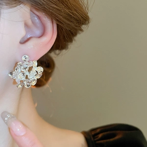 Detailed macro view of silver hollow floral stud earrings with vintage metallic texture