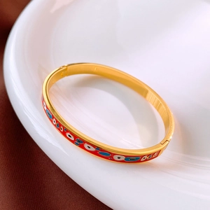 Gros plan d'un bracelet en émail doré avec motifs colorés sur une assiette en porcelaine