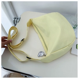 Close-up of yellow canvas crossbody dumpling bag with cute sheep charm and adjustable strap