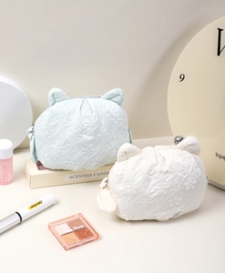 Detail of cute cat ear makeup pouches with floral embroidery and bow accents on soft fabric
