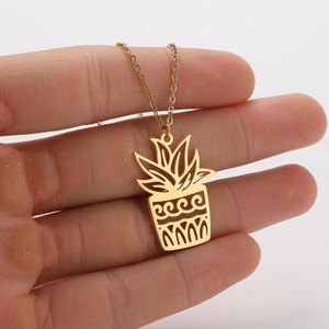 Detailed close-up of a gold plant pot pendant necklace with intricate cutout leaf designs
