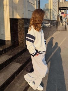 Outdoor street shot of a casual two-piece tracksuit with navy side stripes and wide legs