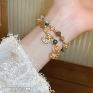 Detail of multilayer freshwater pearl bracelet with vintage gold locket charm on wrist