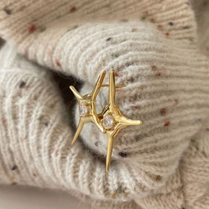 Elegant gold star stud earrings with clear zircon on soft knit fabric background